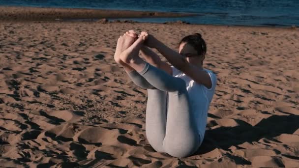 Mujer estirando yoga en la playa junto al río en la ciudad. Hermosa vista . — Vídeos de Stock