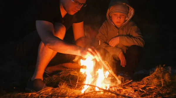 Sohn und Vater entzünden ein Feuer im Wald. Familiencamping. — Stockfoto