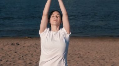 Şehrin nehir kenarında kumsalda Yoga esneme kadın. Güzel bir şehir manzarası. Namaste poz.