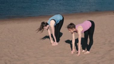 İki şehrin nehir kenarında kumsalda yoga yaparken kadın. Harika bir manzara.