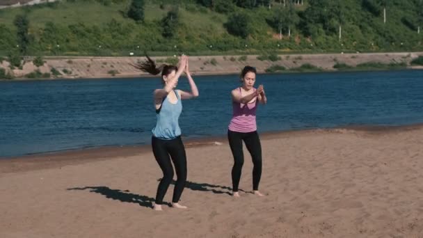 두 여자는 도시에 있는 강 유역에 연습 스포츠를 하 고. 앉아 위치에서 점프. — 비디오