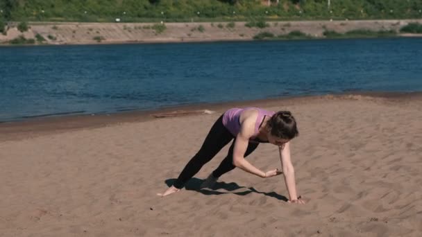 Kvinnan gör övningar sport på stranden av floden i staden. Övningar för händer i plankan. — Stockvideo