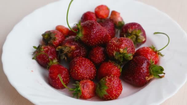 Saftiga aptitretande välsmakande jordgubbar på en vit platta. — Stockvideo