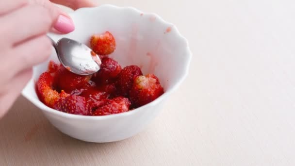 La mujer amasa las fresas con una cuchara y lo mezcla con azúcar, haciendo mermelada. Mano de primer plano . — Vídeos de Stock