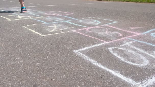 Junge springt beim Hopscotch auf die Straße. Beine aus nächster Nähe. — Stockvideo