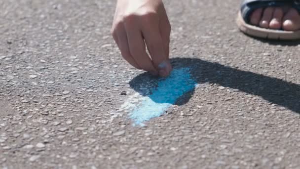 El chico dibuja con tiza azul en el asfalto. Primer plano de las manos . — Vídeos de Stock
