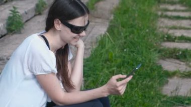 Kadın parkta oturan ve gülümseyerek telefonu bir ileti türleri.