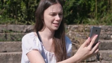 Görüntülü sohbet telefonda: çağrı, söz ve gülümseyen genç kadın.