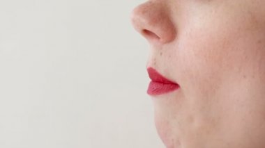 Kadın kırmızı dudaklar ile çilek yiyor. Ağız yakın çekim. Yan görünüm.