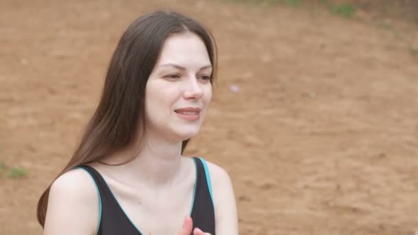 Junge schöne brünette Frau spricht mit jemandem, der auf dem Sand am Strand sitzt. — Stockvideo