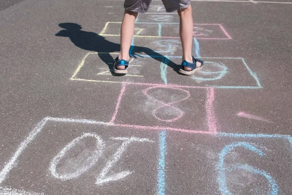 Мальчик прыгает, играя в классики на улице. Крупные ноги . — стоковое фото
