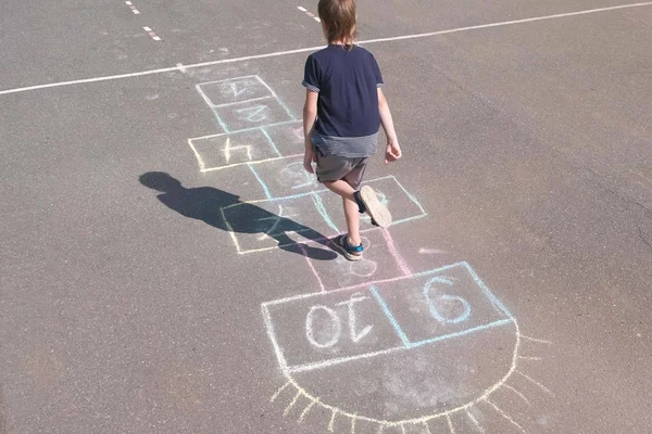 Boy jumps playing hopscotch in the street. — Stock Photo, Image