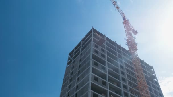 Mehrstöckiges im Bau befindliches Gebäude und Baukran vor dem Hintergrund klaren Himmels. — Stockvideo