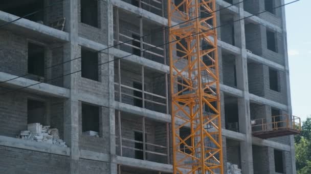 Multi-pisos bajo construcción de construcción y grúa de construcción en el fondo del cielo despejado. Primer plano . — Vídeos de Stock