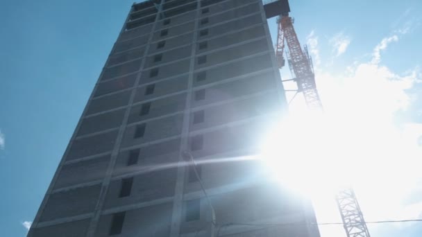 Flera våningar under byggandet byggnad och konstruktion kran på bakgrunden av klar himmel. — Stockvideo