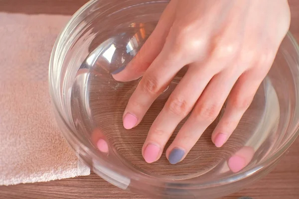Manucure à la maison. Femme trempant sa main dans un bol d'eau. Gros plan de la main . — Photo