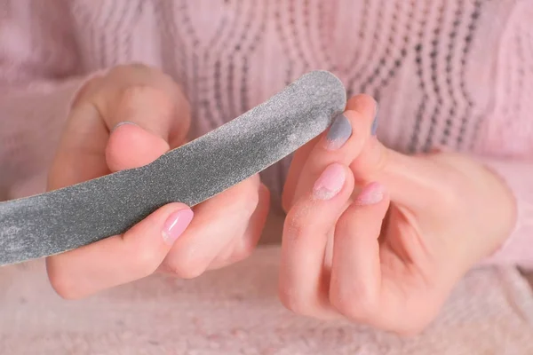 La mujer se pule las uñas con una lima de uñas antes de quitar la goma laca. Primer plano de las manos . —  Fotos de Stock