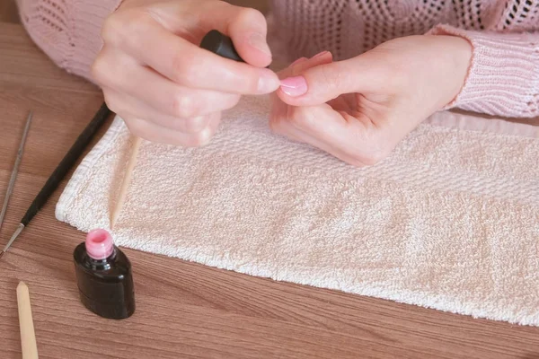 Una donna si mette il primo strato di gommalacca rosa sulle unghie. Mani in primo piano . — Foto Stock