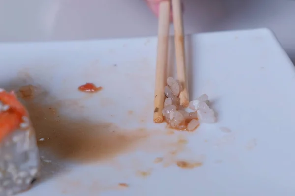 La femme mange des rouleaux avec des baguettes. Gros plan de la main . — Photo