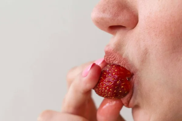 La donna mangia le fragole. Primo piano della bocca. Vista laterale . — Foto Stock