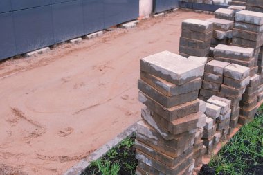 Binanın önünde kaldırım döşeme döşeme. Kum ve kaldırım döşeme satırlardaki. Yakın çekim görünümü.