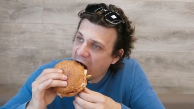 Genç adam bir kafede oturan bir hamburger yeme.