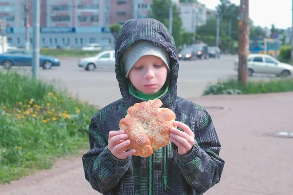 Fiú eszik egy bun, az utcán. — Stock Fotó