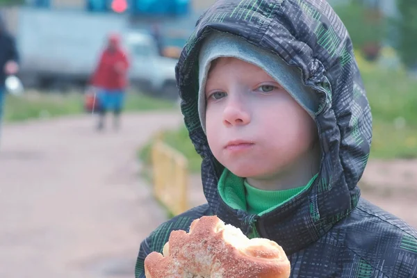 Мальчик ест булочку на улице . — стоковое фото