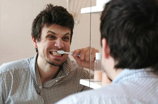 Deli adam fırçala dişlerini onun yansıması Aynaya bakar. — Stok fotoğraf