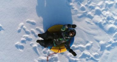 7 yaşında çocuk boru kar üzerinde yatıyor. Yavaş yavaş yükselen kamera. Havadan görüntüleri.