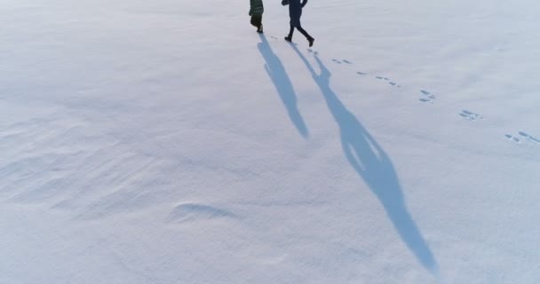 Μαμα και ήλιος τρέχουν μαζί στο χιόνι. Εναέρια πλάνα. Οικογένεια χόμπι το χειμώνα. — Αρχείο Βίντεο