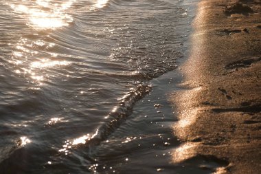 Dalgalar kumlu nehrinde banka günbatımı sırasında.