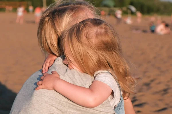 Piękna Blondynka Mama i córka przytulanie na plaży o zachodzie słońca. — Zdjęcie stockowe