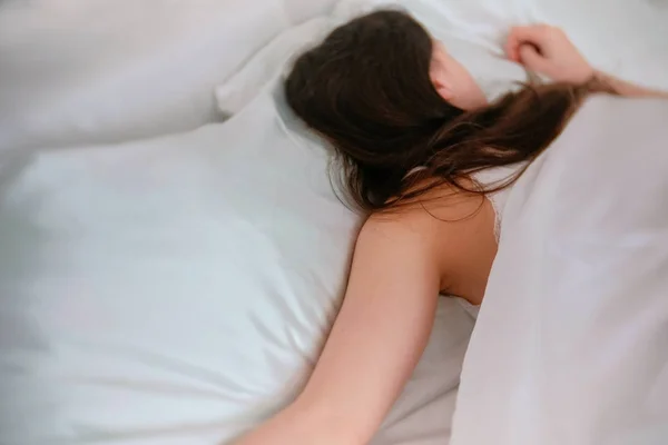 Young woman sleeping in bed. Flips over to the other side.