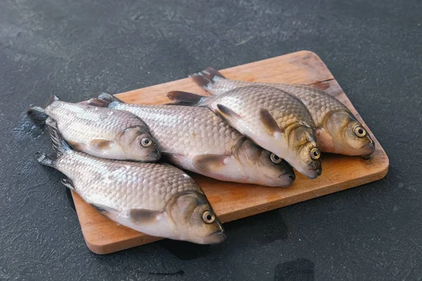 Koken vis. Verse kleine karpers op de tafel op een houten bord close-up. — Stockfoto