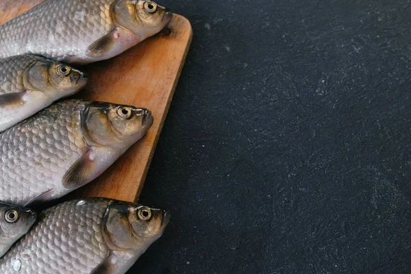 Koken vis. Verse kleine karpers op de tafel op een houten bord close-up. — Stockfoto