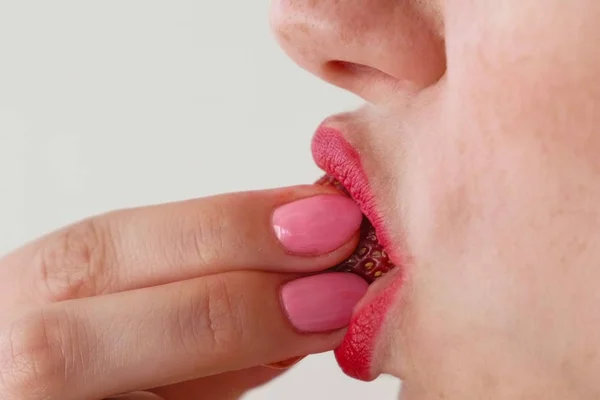 Woman with red lips eats strawberries. Mouth close-up. Side view. — Stock Photo, Image