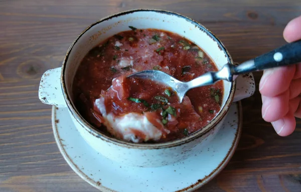 Cibo nazionale russo, zuppa di barbabietole rosse, borscht. Primo piano mans mano con cucchiaio mescolare panna acida nella zuppa . — Foto Stock