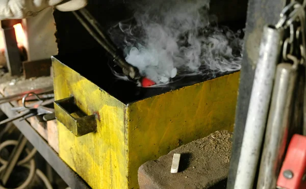 stock image Hardening of the knife blade in a special solution. Close-up of the mans hands dip the knife blade in oil.