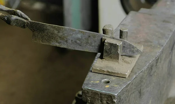 A fazer a faca de metal na forja. Alinhamento das lâminas de faca após o endurecimento do metal . — Fotografia de Stock