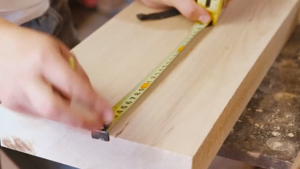 Worker measures the tape measure and pencil distance on the wood Board. Joinery. Hands close-up. — Stock Video