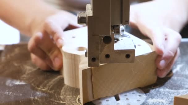 La artesana está cortando una pieza de madera de madera con sierra de cinta. Primer plano de las manos . — Vídeos de Stock