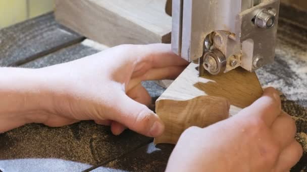 La artesana está cortando una pieza de madera de madera con sierra de cinta. La sierra se rompe durante la operación. Primer plano de las manos . — Vídeo de stock