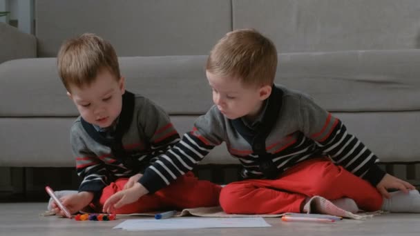 Δύο νήπια αδέλφια δίδυμο συγκεντρώσει δείκτες που κάθεται στο πάτωμα. — Αρχείο Βίντεο
