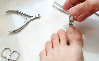 Man cutting toenails with clipper. Male cut toenails on foot. Foot and toes close-up. Top view. clipart