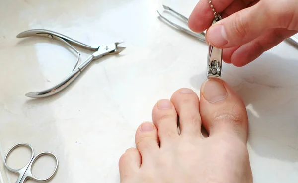 Чоловік ріже нігті за допомогою затискача. Чоловічі нарізані нігті пішки. Ноги і пальці крупним планом. Вид зверху . — стокове фото
