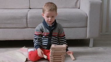Çocuk ahşap bloklar tarafından kanepe katta oturan bir kule inşa ediyor.