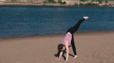 Şehrin nehir kenarında kumsalda yoga yaparken kadın. Güzel manzara. Amut.