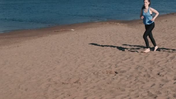 Dos mujeres haciendo estiramientos después de trotar a lo largo de la playa de arena del río al atardecer . — Vídeo de stock