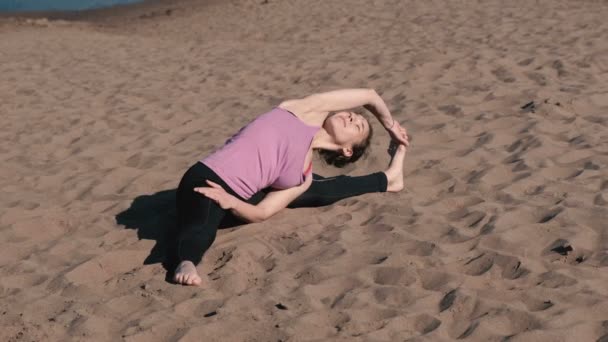 Mujer estirando yoga en la playa de la ciudad. Sirsasana, Supta upavistha konasana pose . — Vídeos de Stock